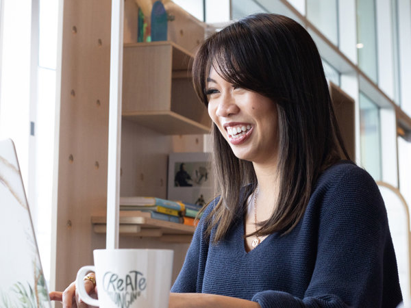 a woman smiling at a coffee cup