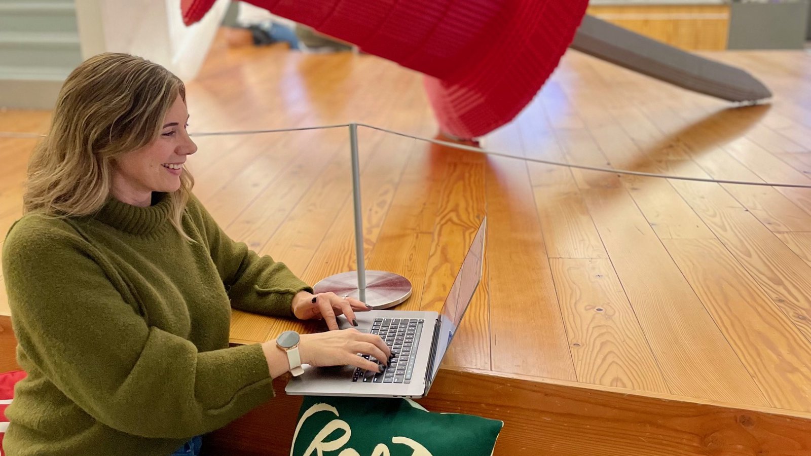 a woman sitting on a wood floor using a laptop