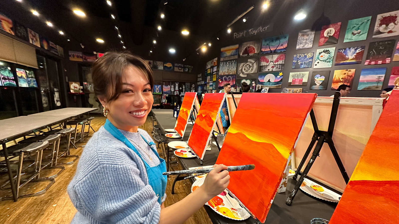 a woman painting on canvas in a room