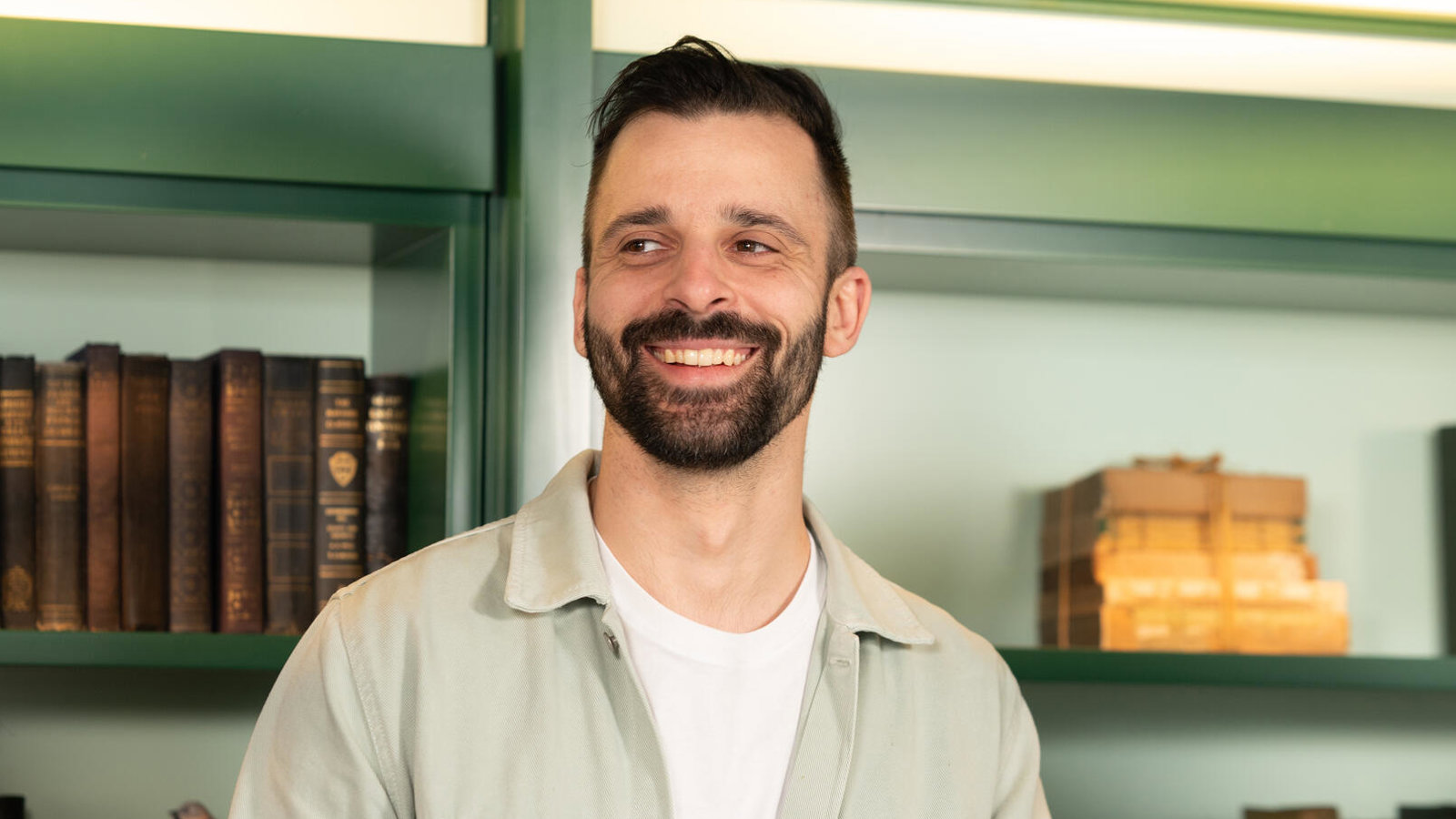 a person smiling in front of a shelf