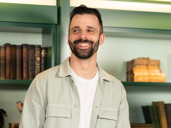 a person smiling in front of a shelf