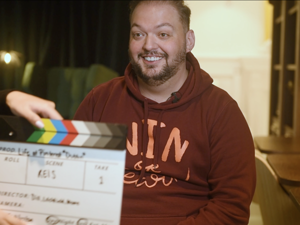a person sitting in front of a movie clapper board
