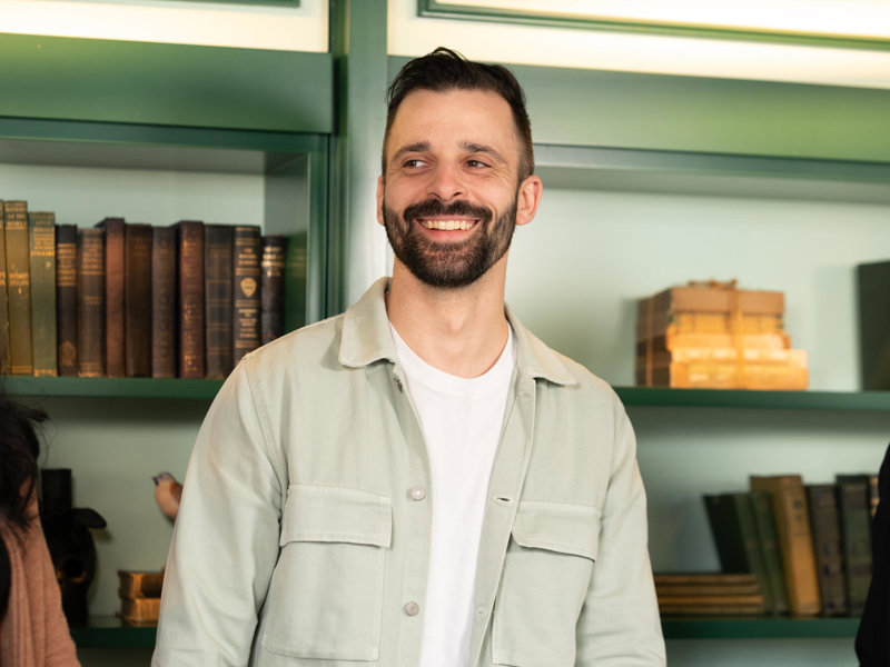 a man smiling in front of a shelf