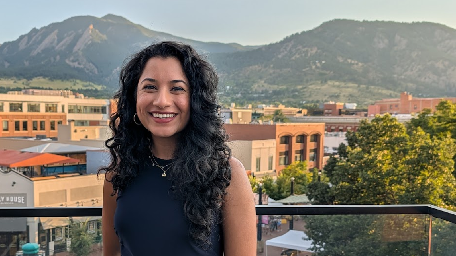 a person standing on a balcony with a view of a town and mountains in the background