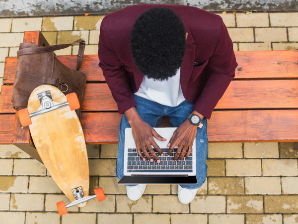 a man sitting on a bench using a laptop