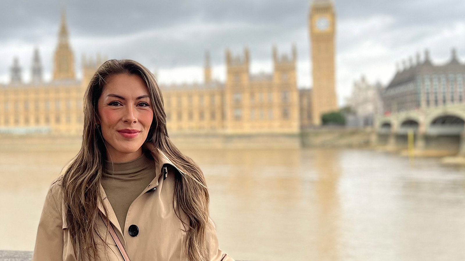a woman standing on a stone ledge in front of a large building