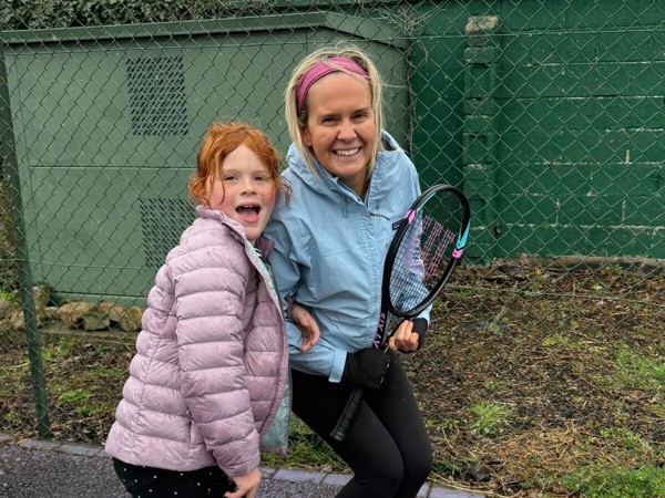 a person and a child holding tennis rackets