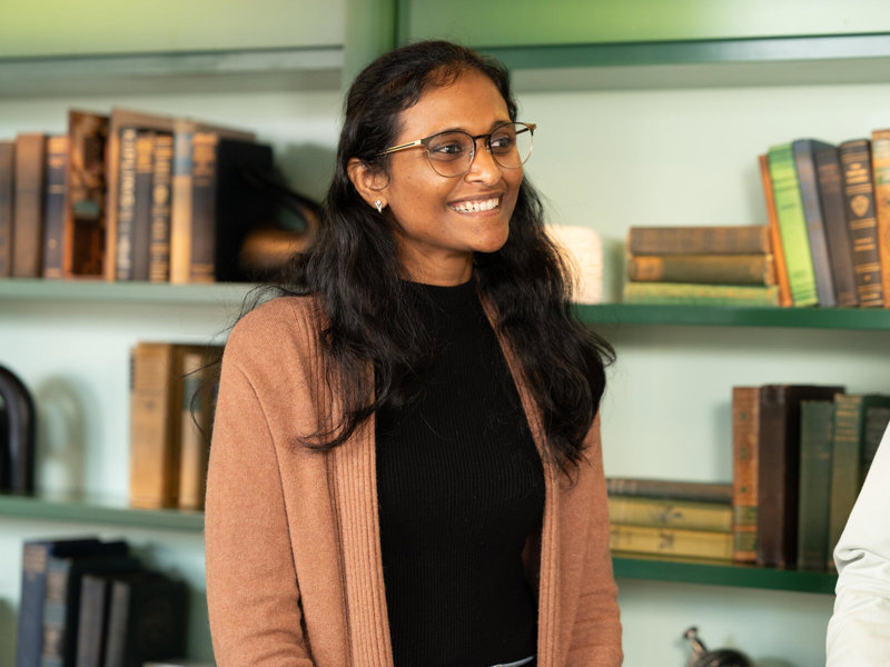 a woman smiling in front of a book shelf