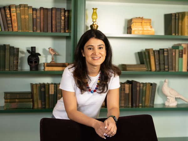 a woman leaning on a couch in front of a bookshelf