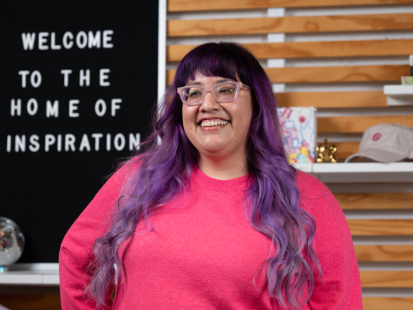 a person with purple hair and glasses smiling