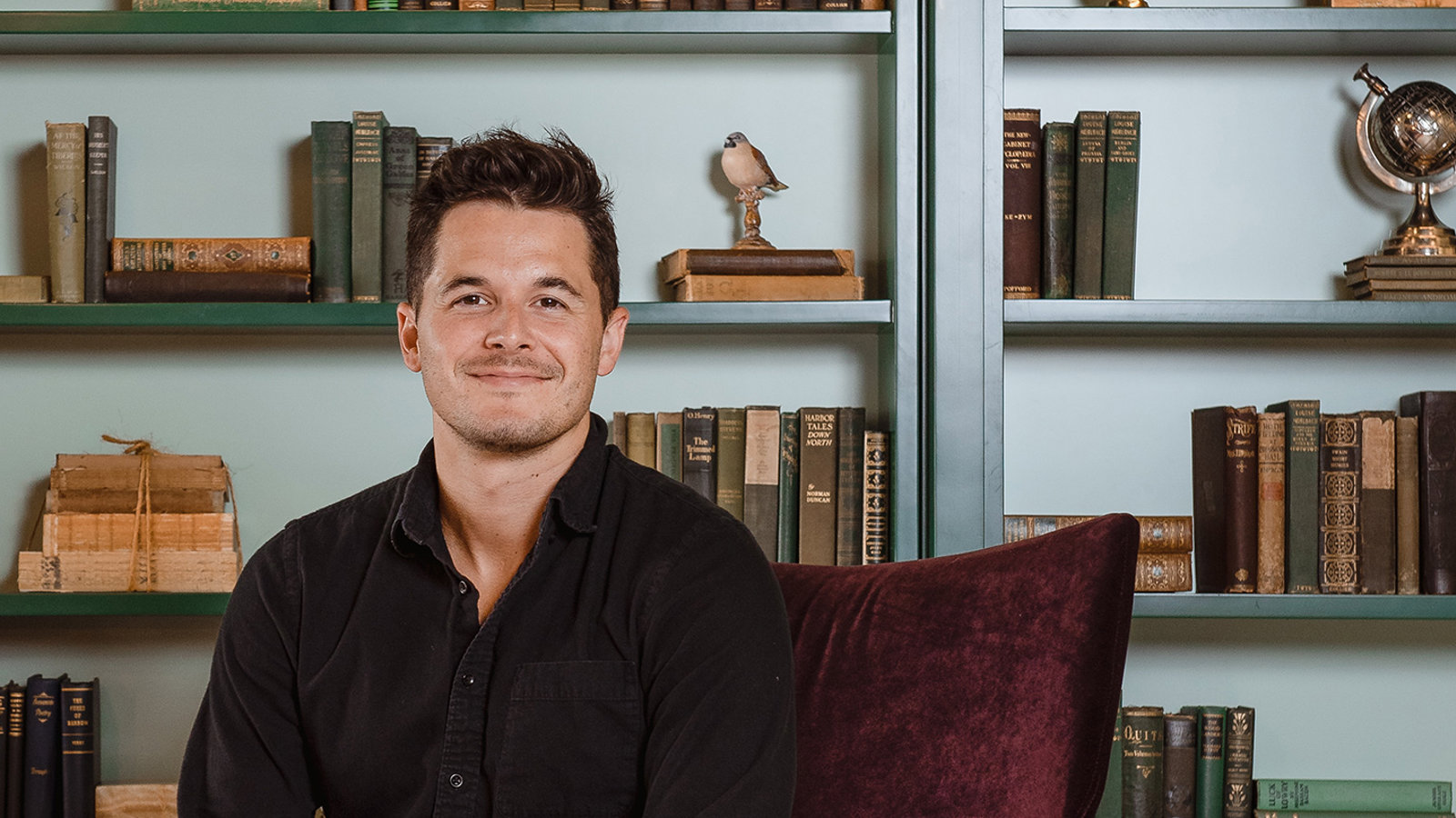 a man sitting in a chair in front of a bookcase