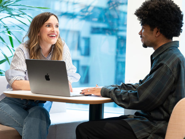 a person and person sitting at a table with a laptop