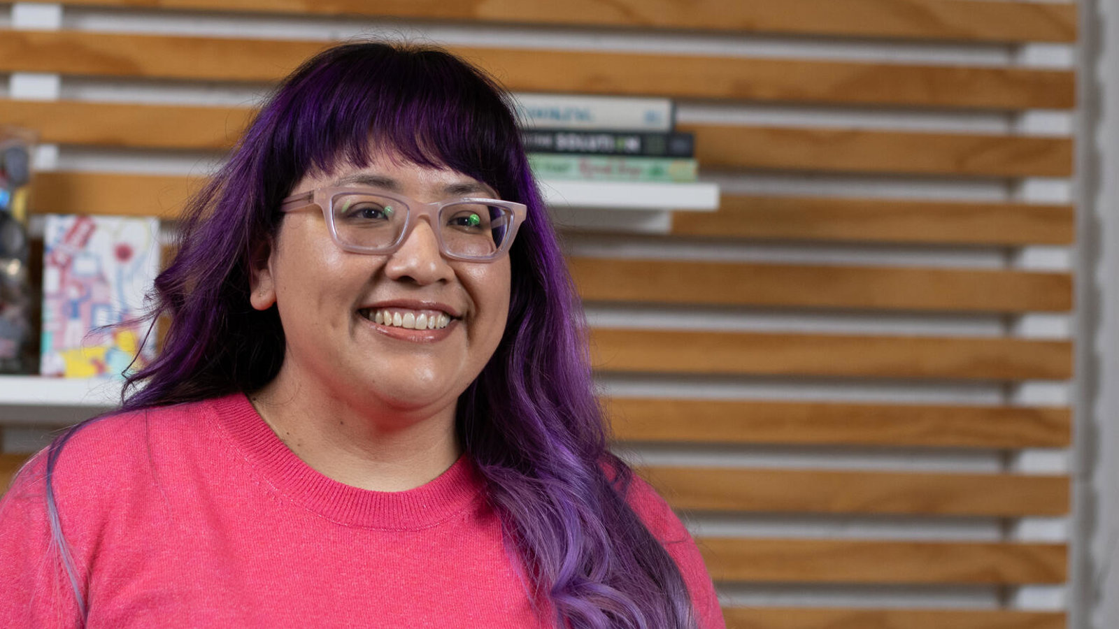 a woman with purple hair and glasses smiling