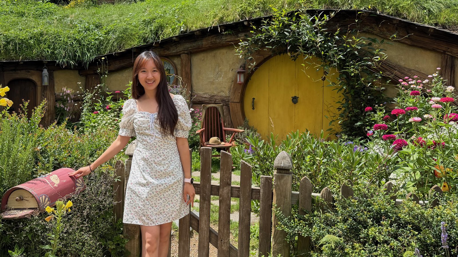 a person in a dress holding a mailbox in front of a house